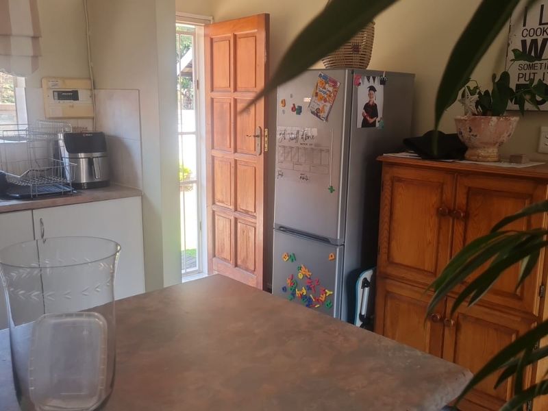 A functional kitchen area featuring laminate countertops, built-in cabinetry, and direct access to the exterior through a timber door.