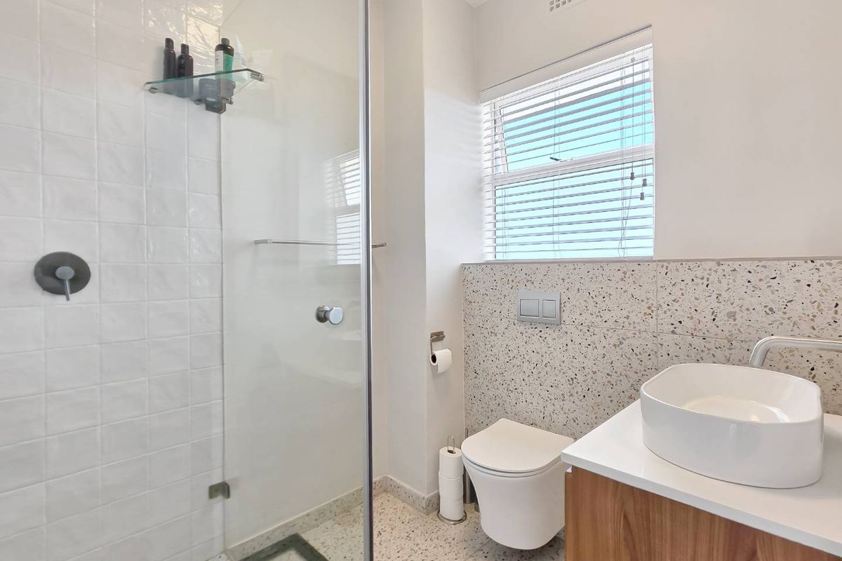 Modern bathroom featuring a glass-enclosed shower, wall-hung toilet with concealed cistern, vessel sink vanity, and stylish terrazzo finishes.
