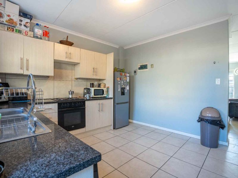 Functional kitchen featuring light-toned built-in cabinetry, granite countertops, a built-in oven, and tiled flooring, offering a practical layout for daily use.