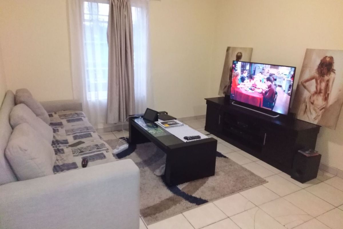 A standard living room featuring tiled flooring and a window with curtain fixtures, providing a functional and neutral space for relaxation.
