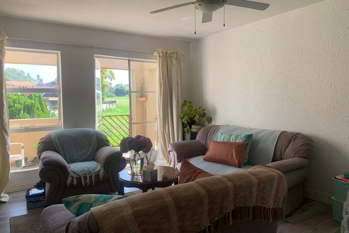 A comfortable living room featuring a ceiling fan and direct access to a private balcony with scenic views.
