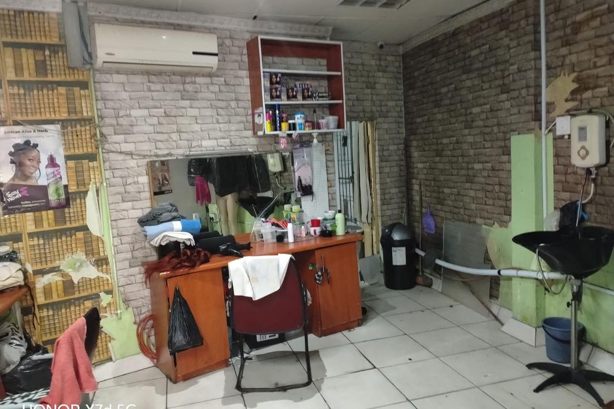 A functional utility space currently utilized as a salon, featuring tiled flooring, a wall-mounted basin, and built-in vanity cabinetry.