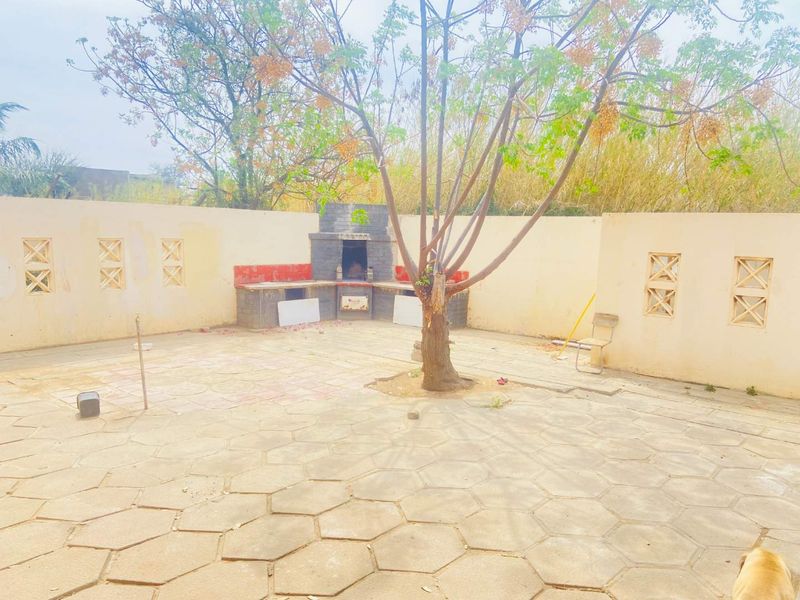 Outdoor patio area featuring a built-in brick barbecue, paved flooring, and perimeter walls with decorative ventilation inserts.