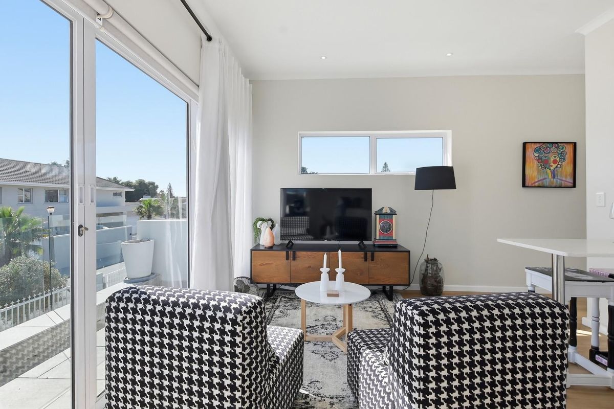 Bright living room featuring large sliding glass doors that provide ample natural light and access to an outdoor balcony area.