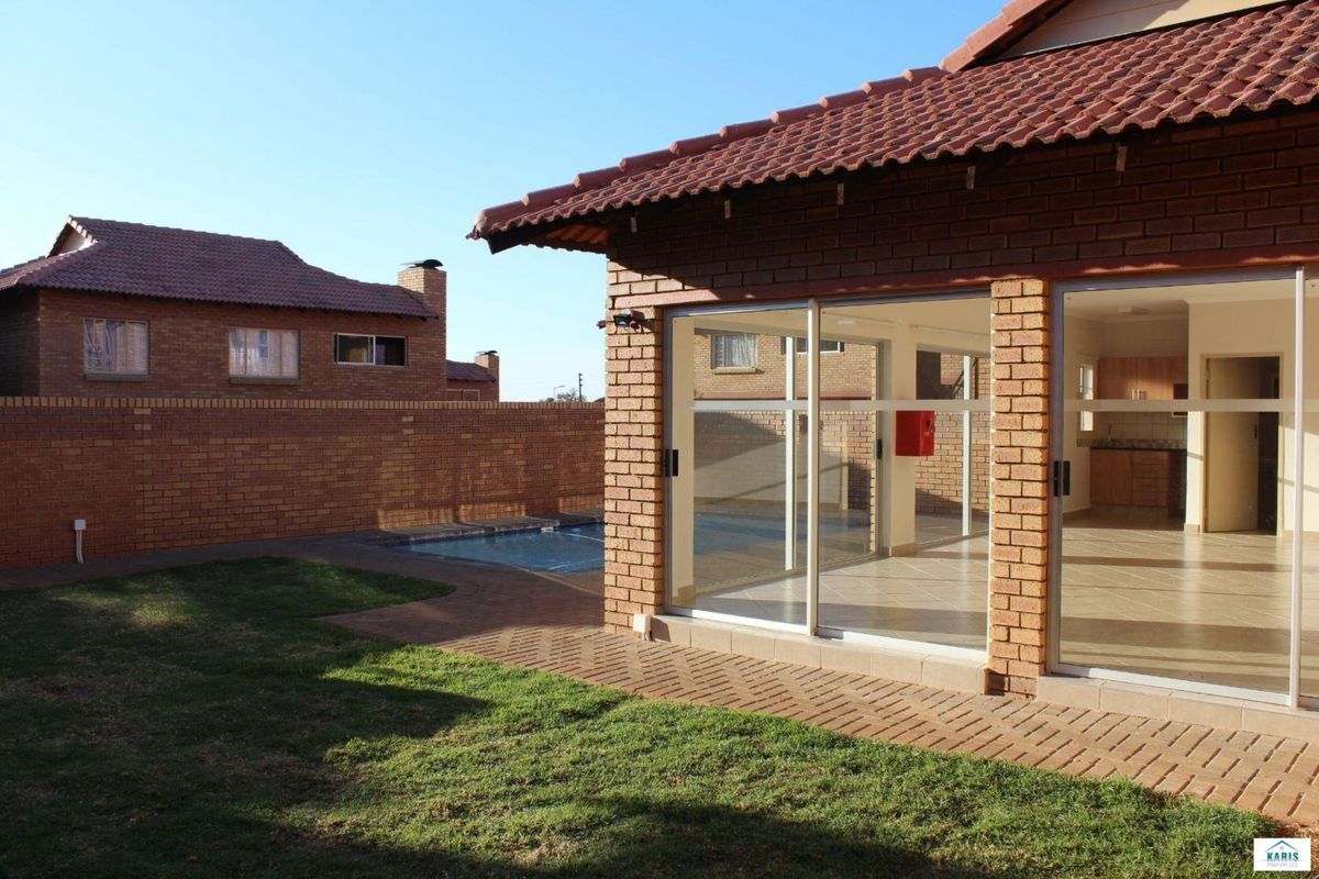 Rear view of the property featuring a private swimming pool, paved patio area, and sliding glass doors leading into the living space.