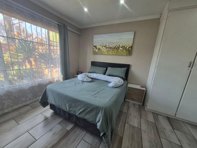 A well-maintained bedroom featuring modern tiled flooring, built-in cupboards, and recessed downlighting, offering a comfortable and functional living space.
