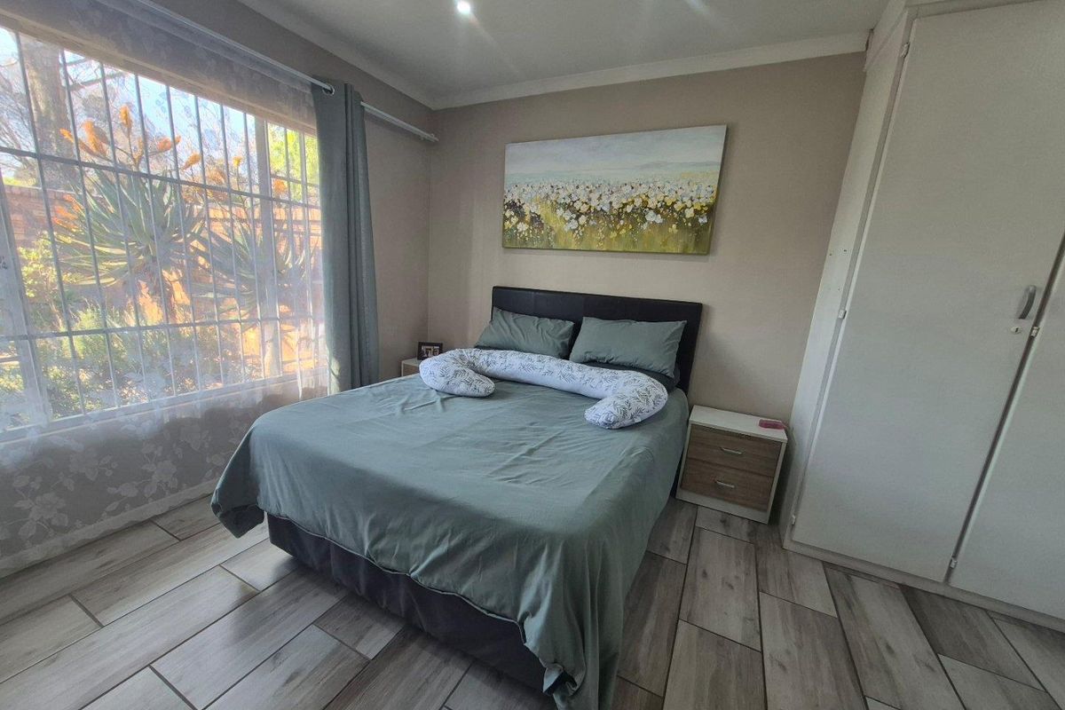A well-maintained bedroom featuring modern tiled flooring, built-in cupboards, and recessed downlighting, offering a comfortable and functional living space.