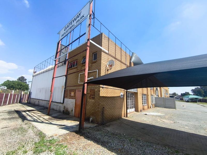 Exterior view of the Gateway Industrial Park building featuring face brick construction, a large signage frame, and a covered parking area.