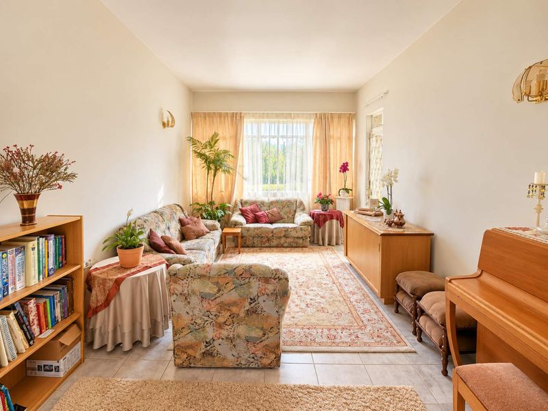 A spacious and well-lit living room featuring neutral tiled flooring and a large window that allows for ample natural light.