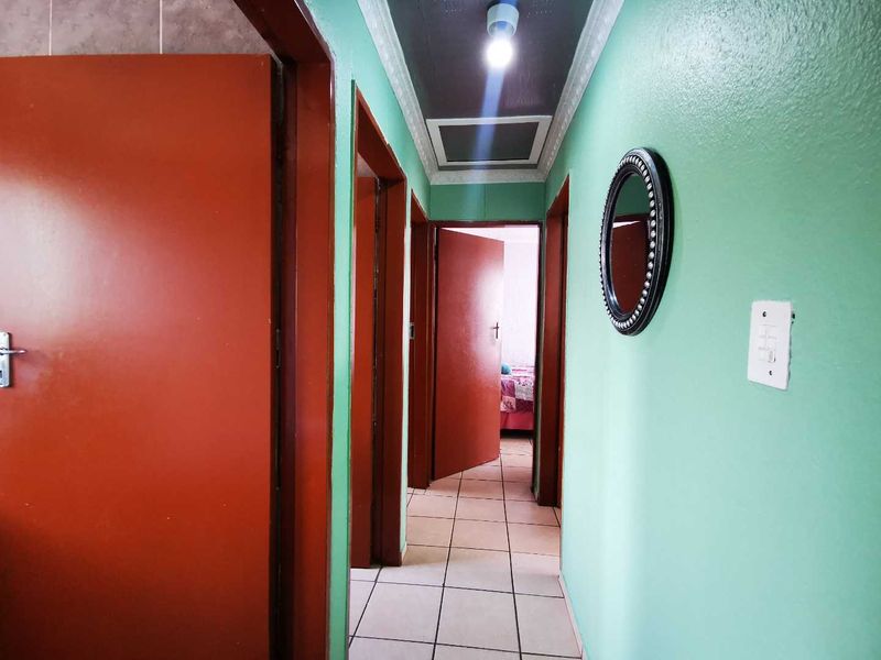 A functional hallway featuring tiled flooring, coved ceilings, and multiple internal access points, providing a central connection between rooms.