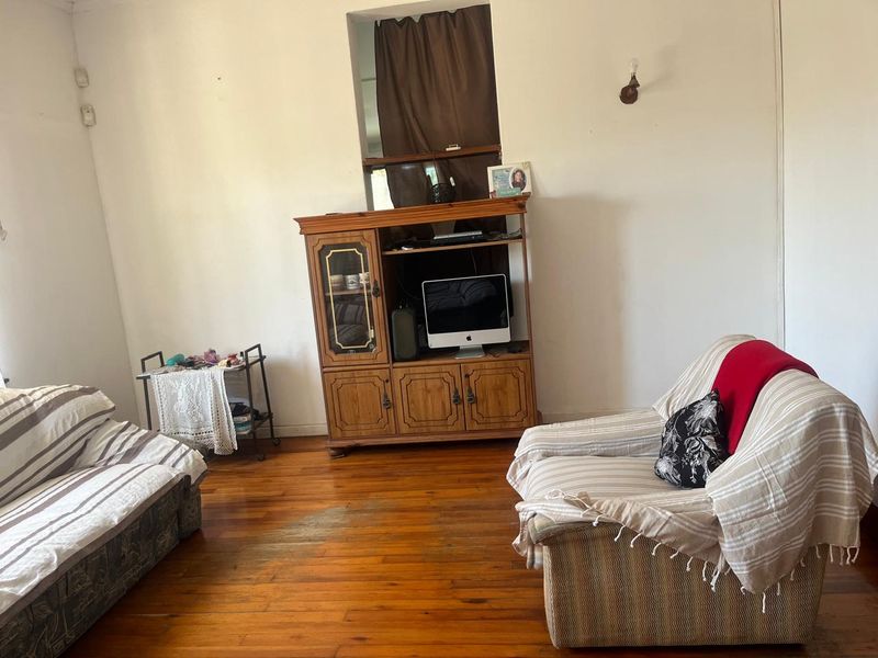 A living room featuring original hardwood flooring and neutral wall finishes, offering a blank canvas for potential renovation and interior design updates.