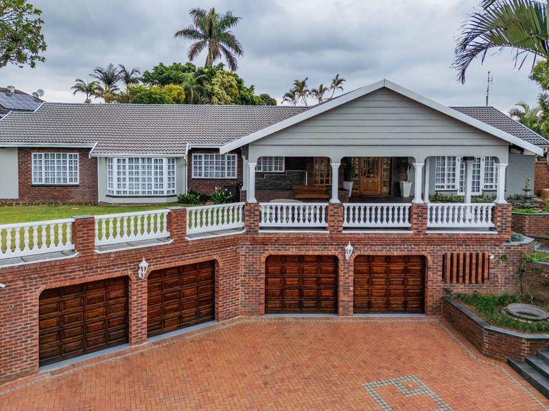 A well-maintained single-story residence featuring a brick facade, triple garage, and a spacious covered patio with classic balustrade detailing.