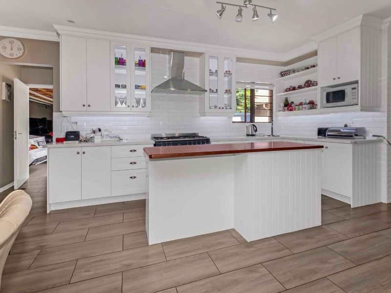 Modern kitchen featuring white shaker cabinetry, subway tile backsplash, stainless steel appliances, and a central island with a wood countertop.