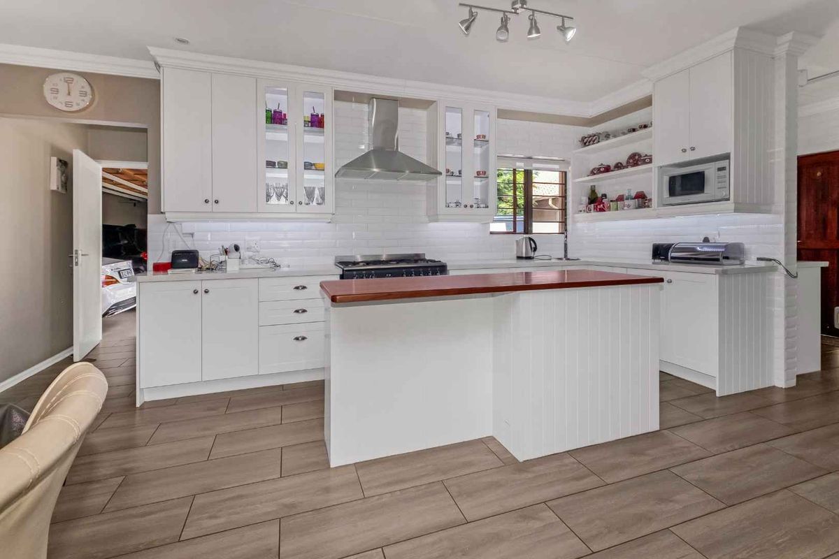 Modern kitchen featuring white shaker cabinetry, subway tile backsplash, stainless steel appliances, and a central island with a wood countertop.