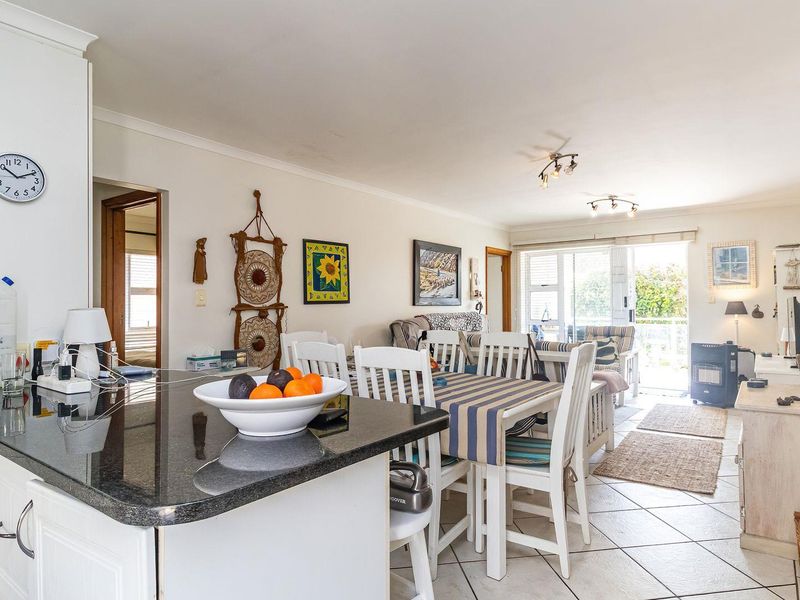 Open-plan living and dining area featuring a kitchen with granite countertops, tiled flooring, and direct access to an outdoor balcony through sliding glass doors.