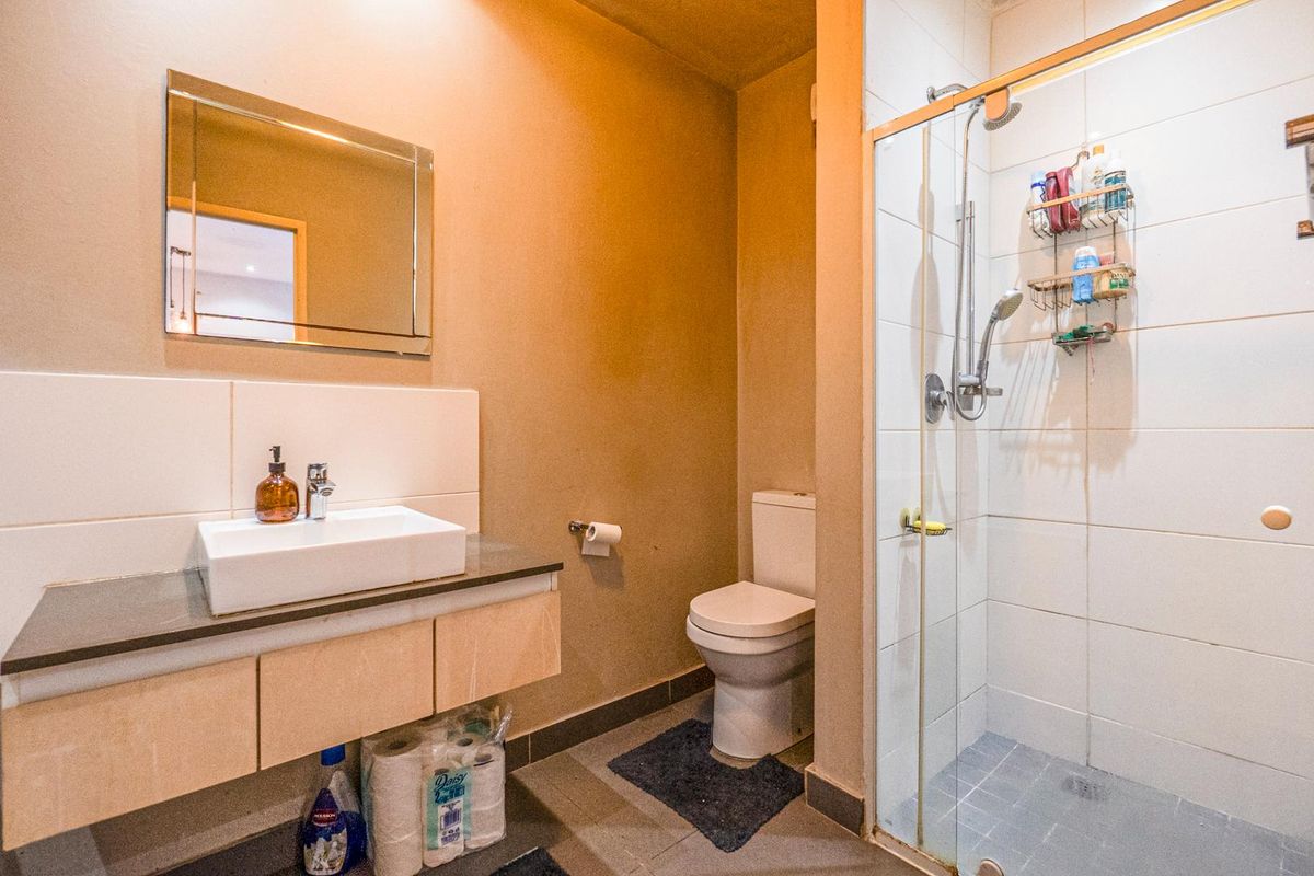 A functional bathroom featuring a modern vessel sink vanity, a glass-enclosed shower, and a standard toilet with tiled flooring.