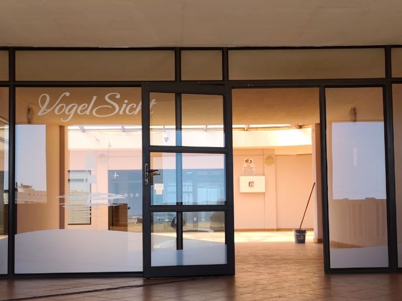 Entrance area featuring an aluminium frame glass door and tiled flooring, currently utilized as a commercial space.
