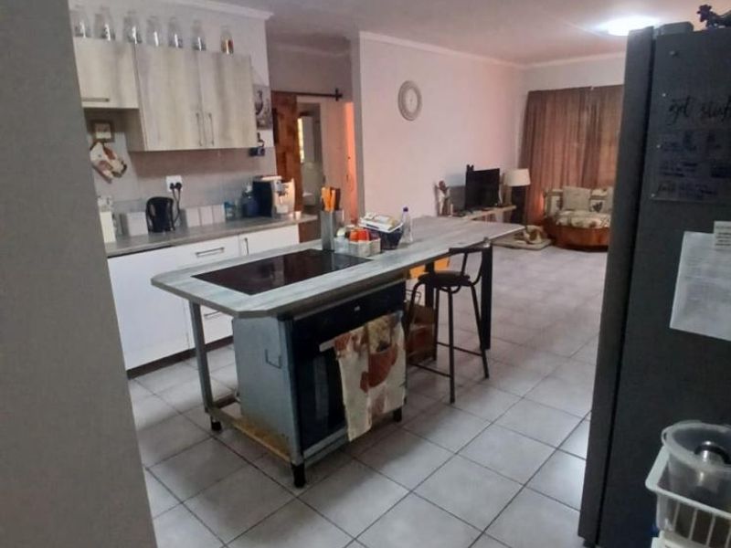 Open plan kitchen and living area featuring tiled flooring, modern cabinetry, and a central island with a built-in hob and oven.