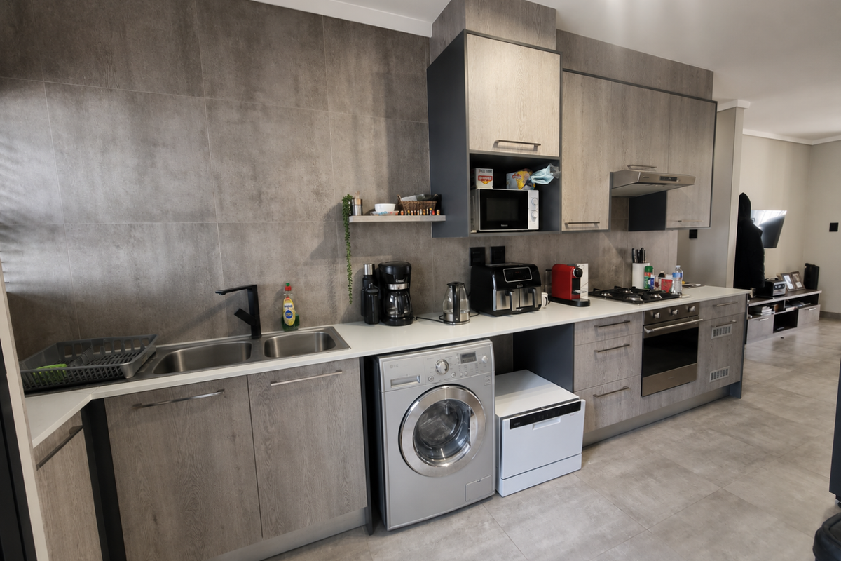Modern kitchen featuring wood-grain cabinetry, stone countertops, integrated appliances, and large-format tiled splashbacks, offering a clean and contemporary aesthetic.