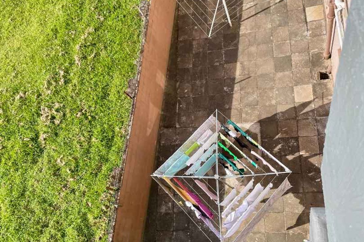 An elevated view of a paved rear courtyard area featuring a retaining wall and grass verge, suitable for outdoor improvement.