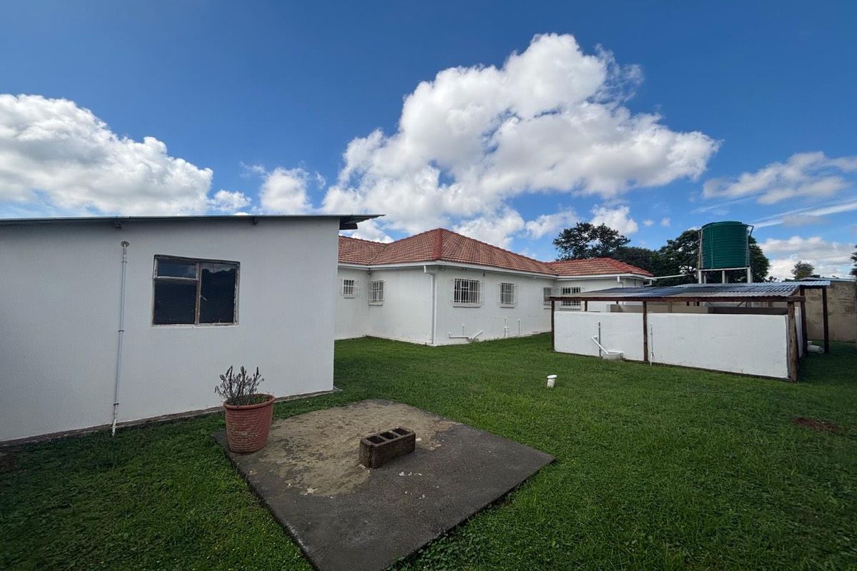 Rear view of the farm property featuring a lawn, a concrete patio area, and a water storage tank.