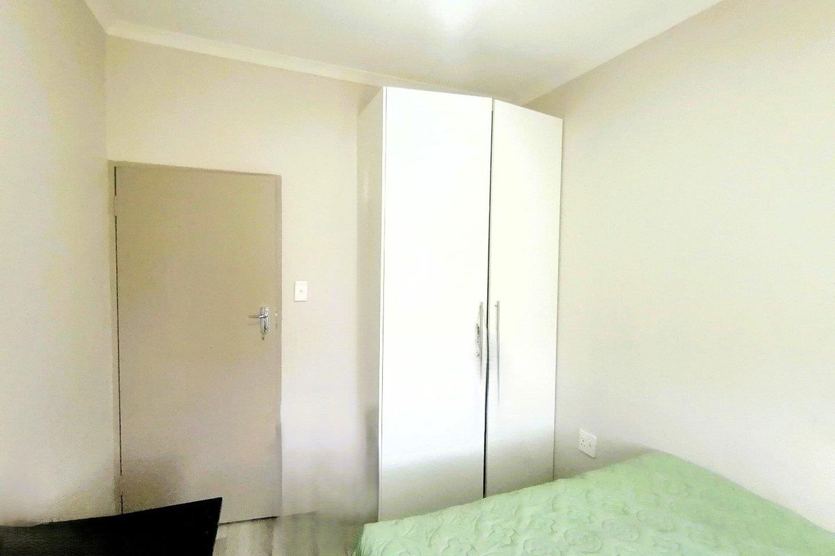 A bedroom featuring a built-in white wardrobe and neutral wall finishes.
