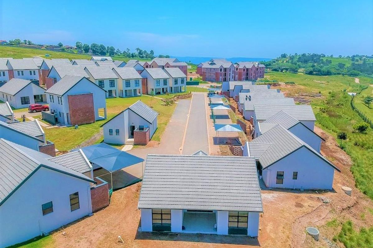 Aerial view of a residential townhouse development featuring multiple units with tiled roofs, paved driveways, and carport structures in a suburban setting.