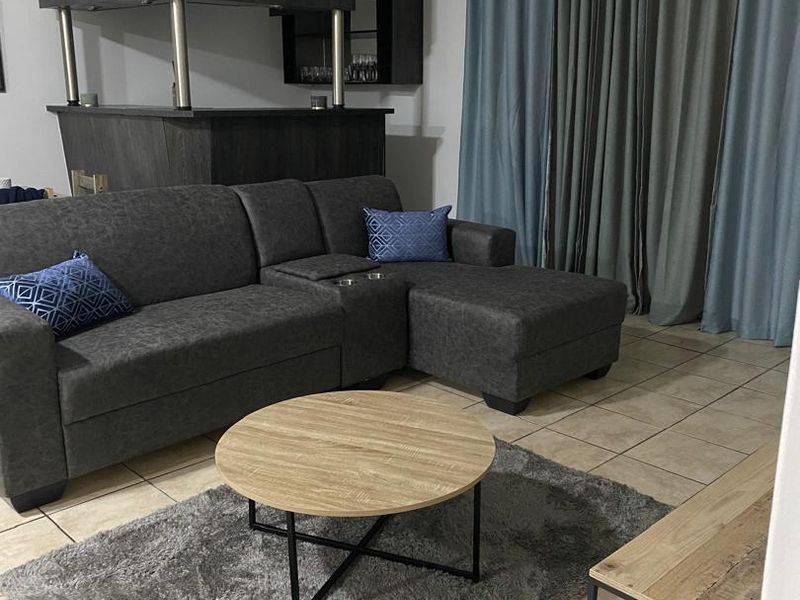 A living room area featuring tiled flooring and a built-in bar counter, providing a functional space for relaxation and entertainment.