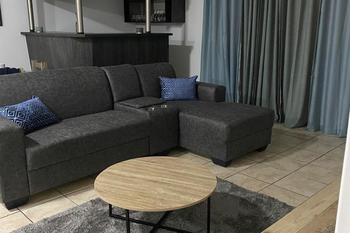 A living room area featuring tiled flooring and a built-in bar counter, providing a functional space for relaxation and entertainment.