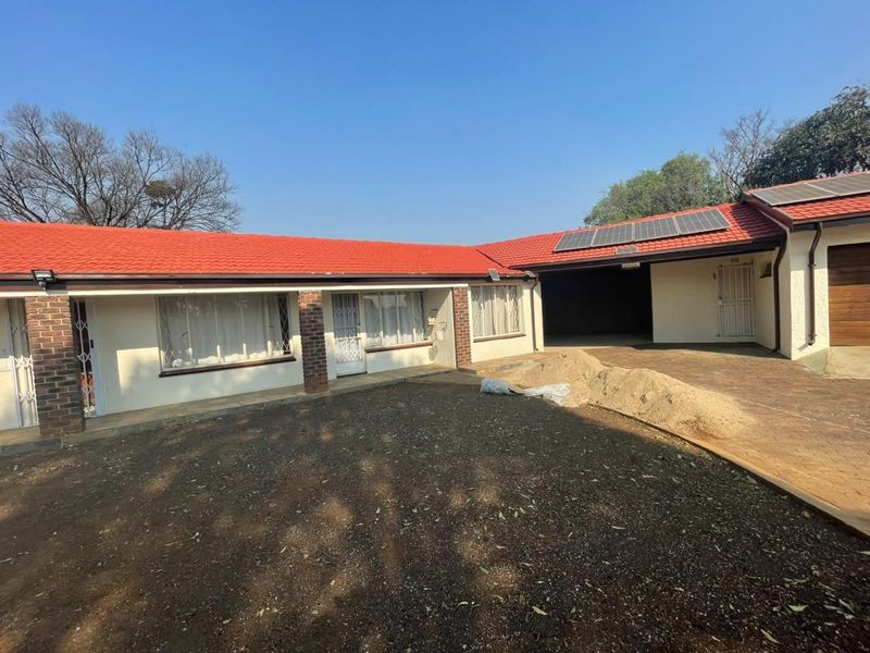 Front exterior view of a cluster home featuring a red tile roof, solar panels, brick accents, and a paved driveway with an attached garage.