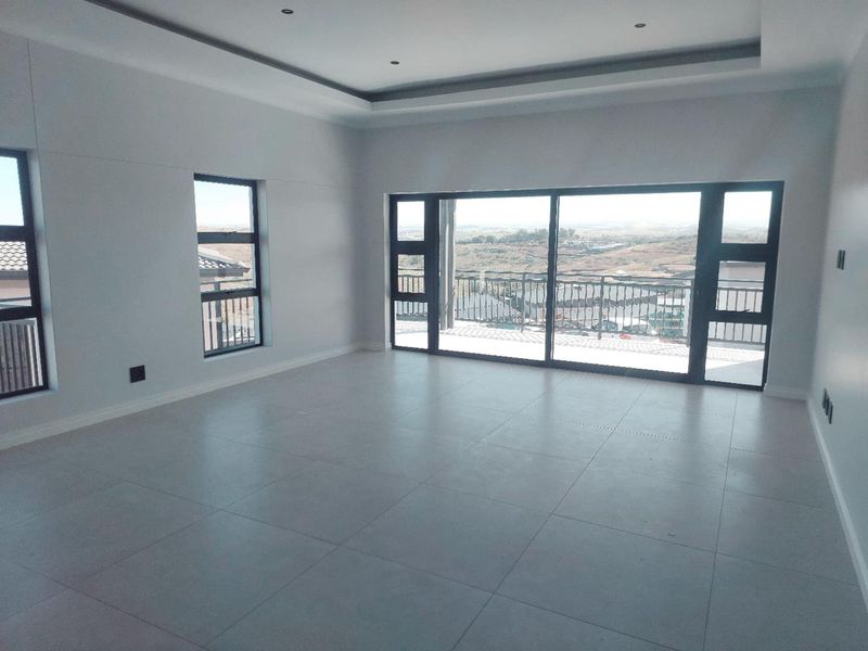 Spacious, modern living area featuring large sliding glass doors, tiled floors, and a recessed ceiling with a scenic outdoor view.