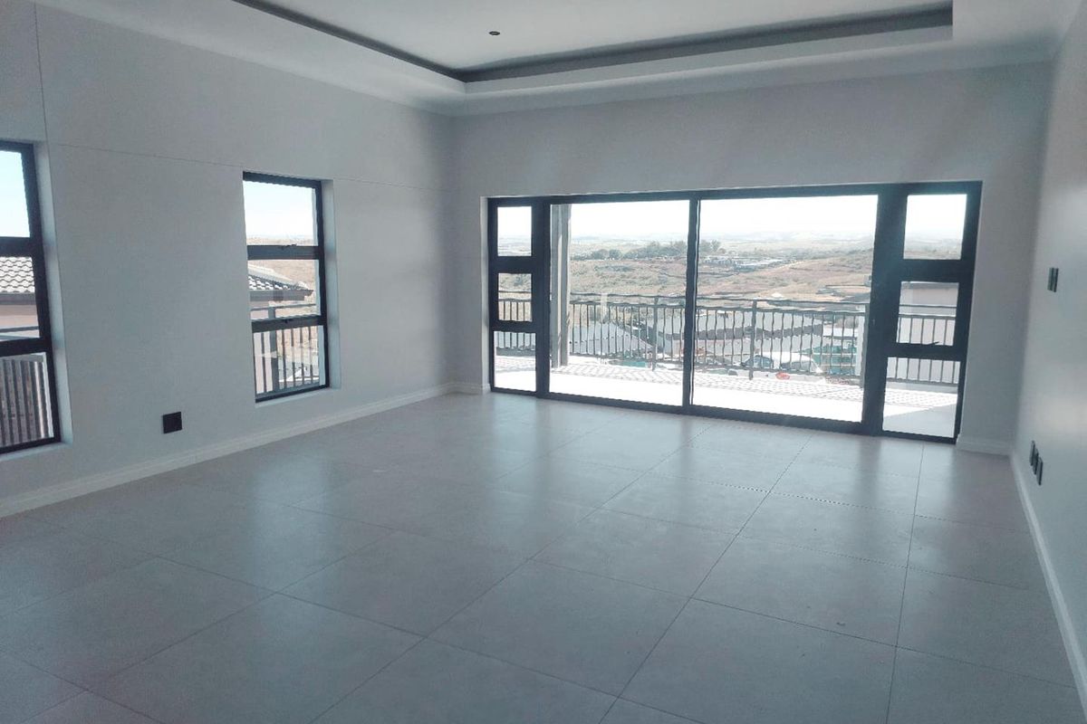 Spacious, modern living area featuring large sliding glass doors, tiled floors, and a recessed ceiling with a scenic outdoor view.