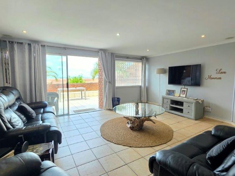 Spacious living room featuring tiled flooring, recessed lighting, and a sliding glass door providing direct access to an outdoor patio area.