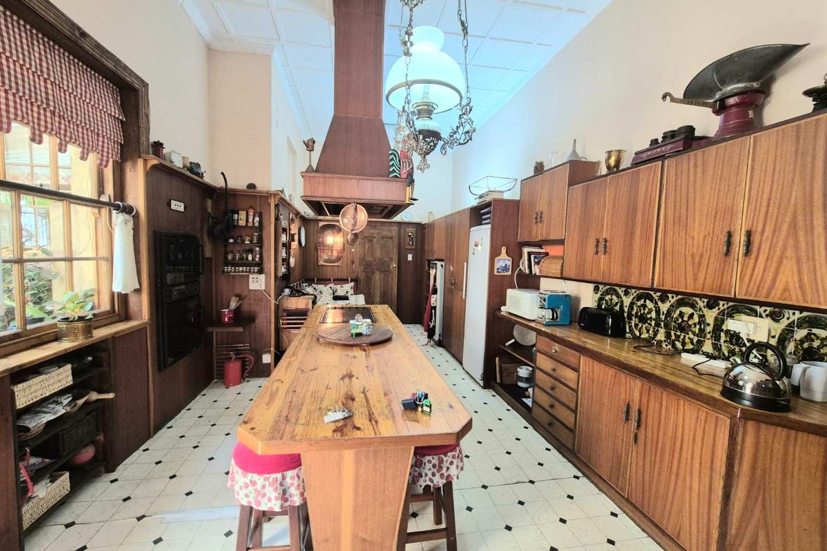 A spacious, rustic-style kitchen featuring extensive wooden cabinetry, a central island with a built-in cooktop, and a large overhead extractor hood.