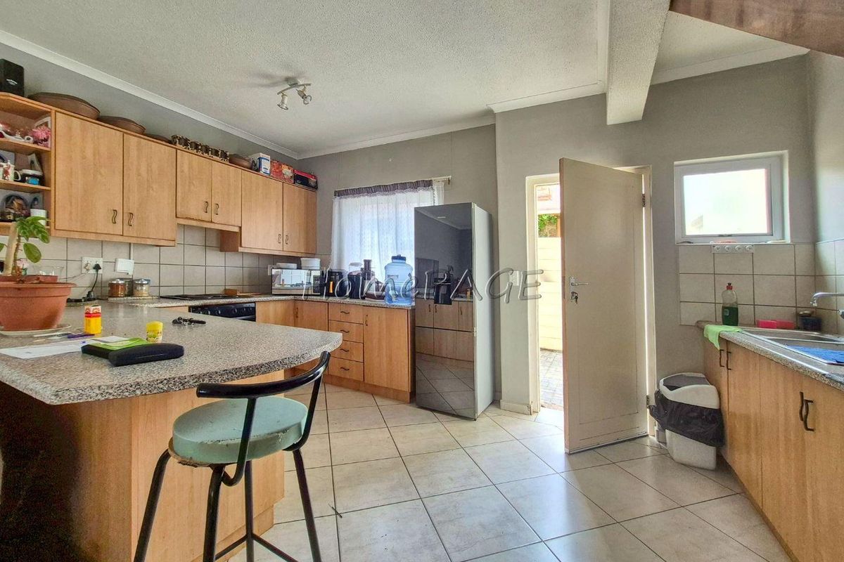 Functional kitchen featuring wood-veneer cabinetry, granite-look countertops, tiled flooring, and direct access to an outdoor area.