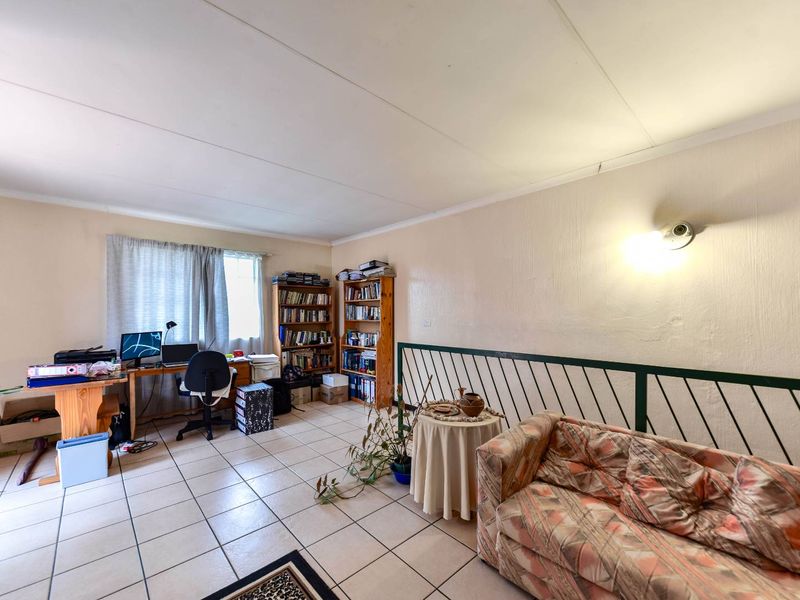 A living area featuring tiled flooring and a metal balustrade, offering a functional space with potential for modern updates.