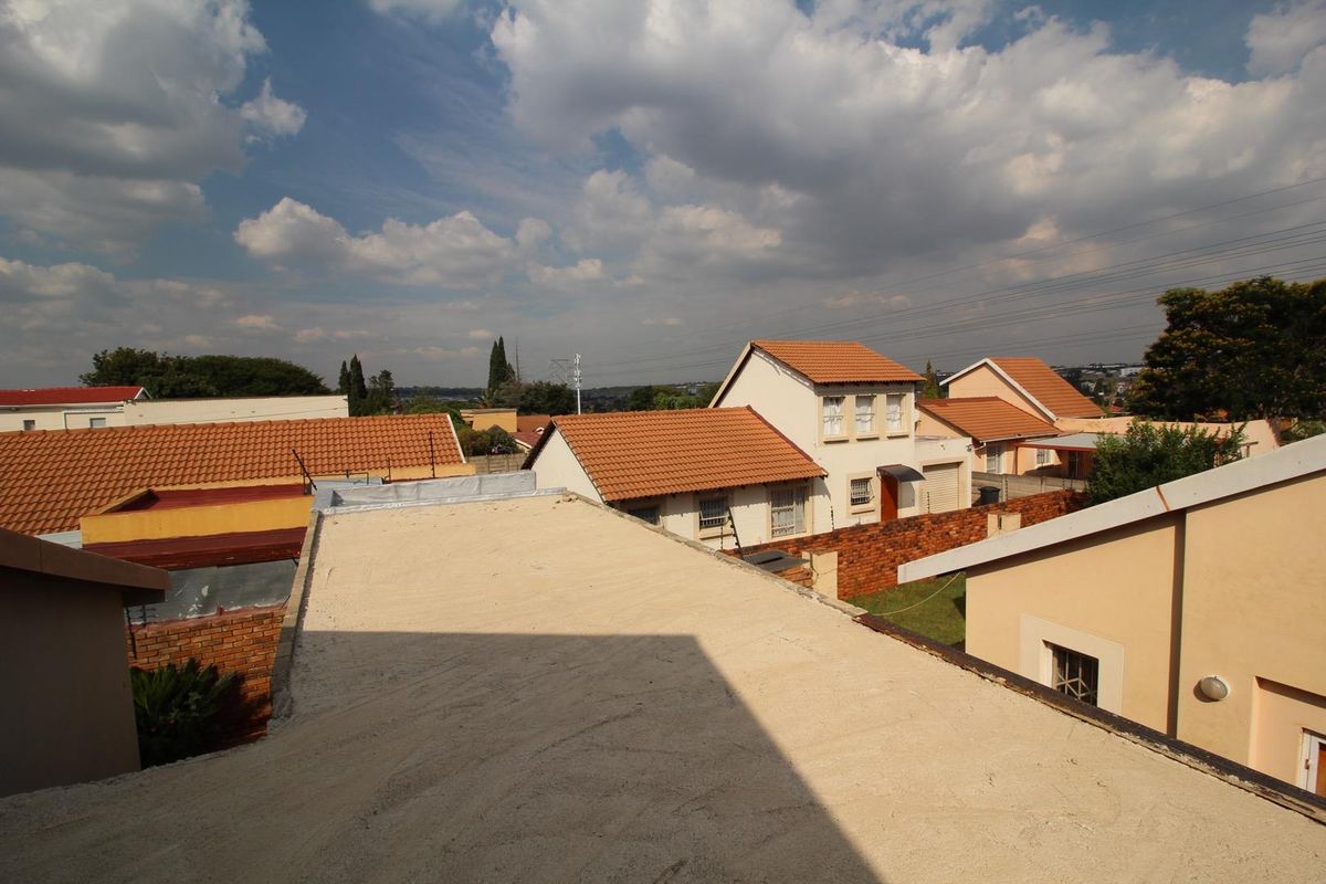An elevated view overlooking the surrounding residential neighborhood, featuring tiled roof structures and an unfinished flat roof section in the foreground.