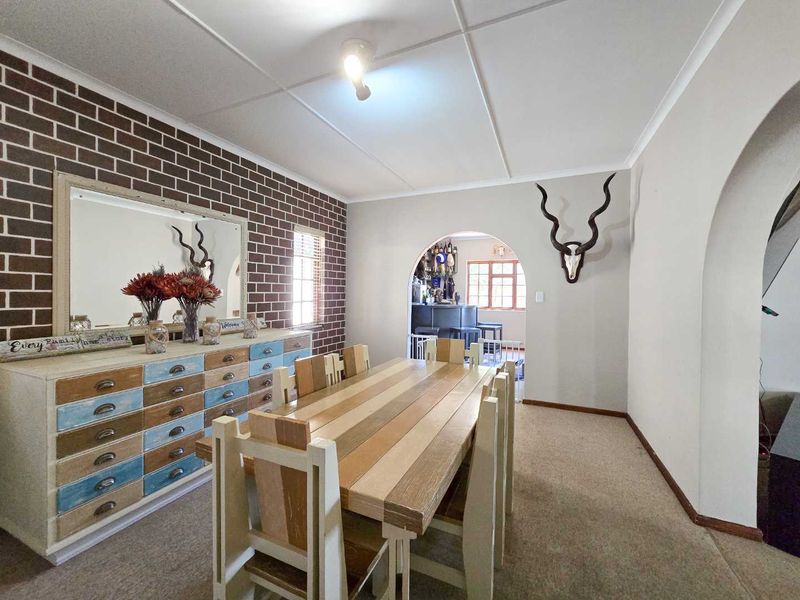 Dining room featuring a brick-style accent wall, arched doorway leading to an adjacent space, and neutral carpeting.