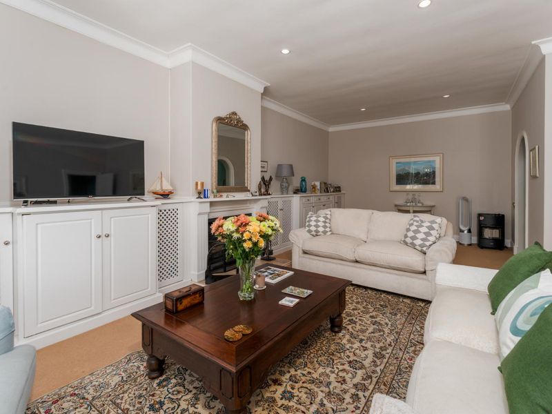 A well-maintained living room featuring built-in cabinetry, a fireplace, recessed lighting, and elegant crown molding.