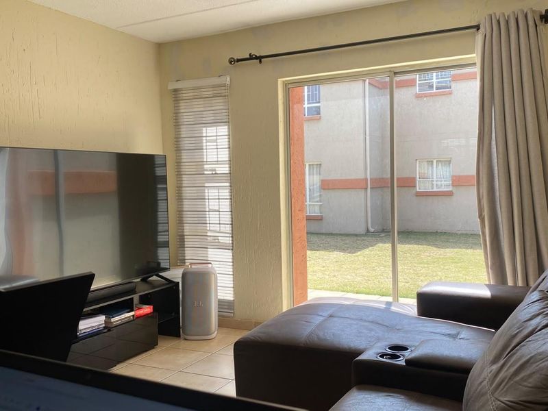 A living room featuring tiled floors and a large sliding glass door providing access to the exterior, with visible wear on the wall finishes.
