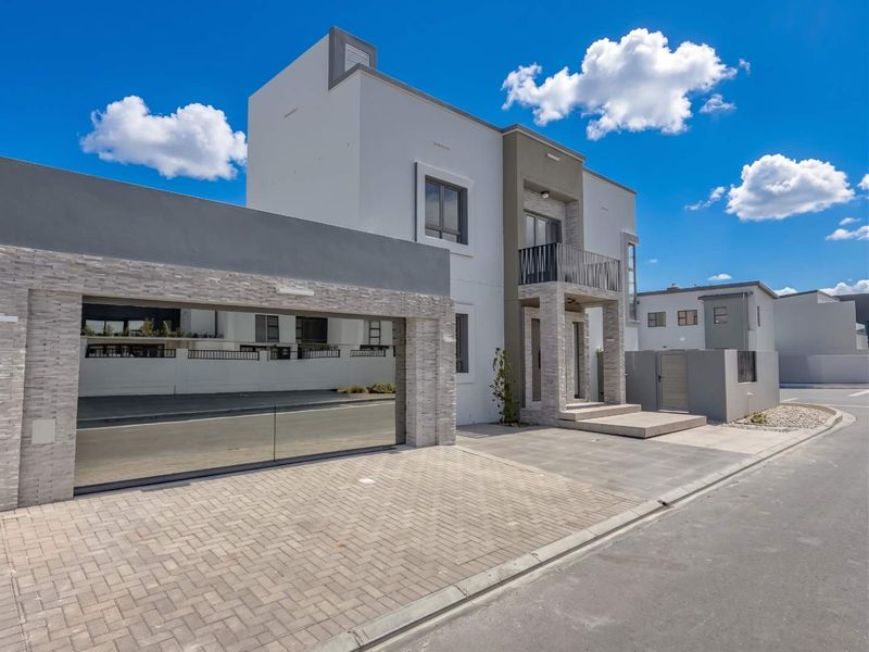 Modern double-storey residence featuring a paved driveway, integrated double garage, stone-clad accents, and a private balcony.