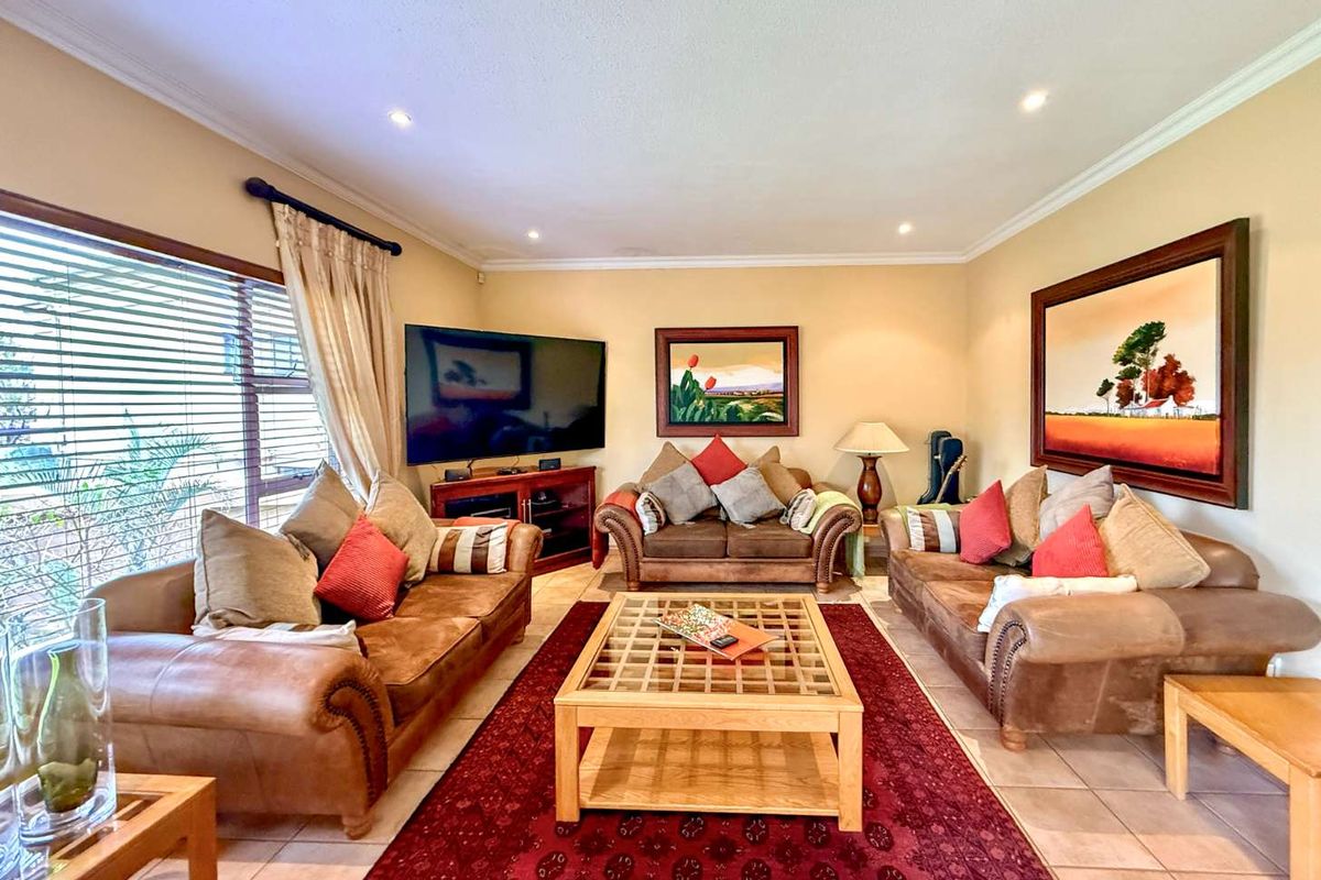A comfortable living room featuring tiled flooring, recessed downlighting, and large windows that provide ample natural light.