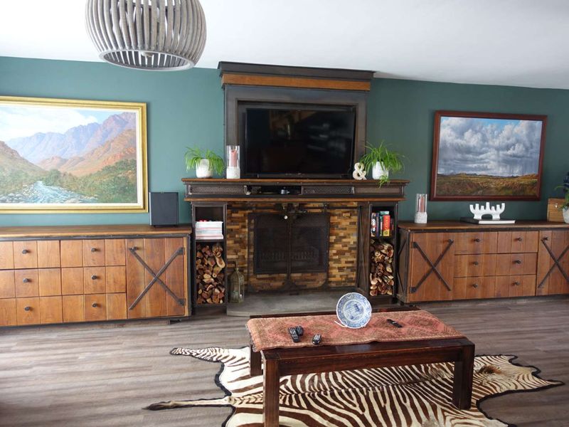 A well-appointed living room featuring a prominent built-in fireplace with integrated storage cabinetry and modern laminate flooring.