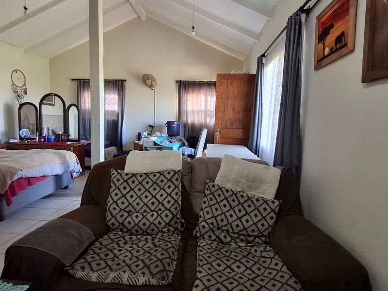 Spacious bedroom featuring a high vaulted ceiling, tiled flooring, and an open-plan layout with natural light.