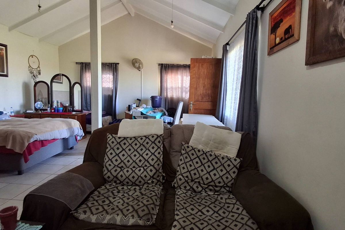 Spacious bedroom featuring a high vaulted ceiling, tiled flooring, and an open-plan layout with natural light.