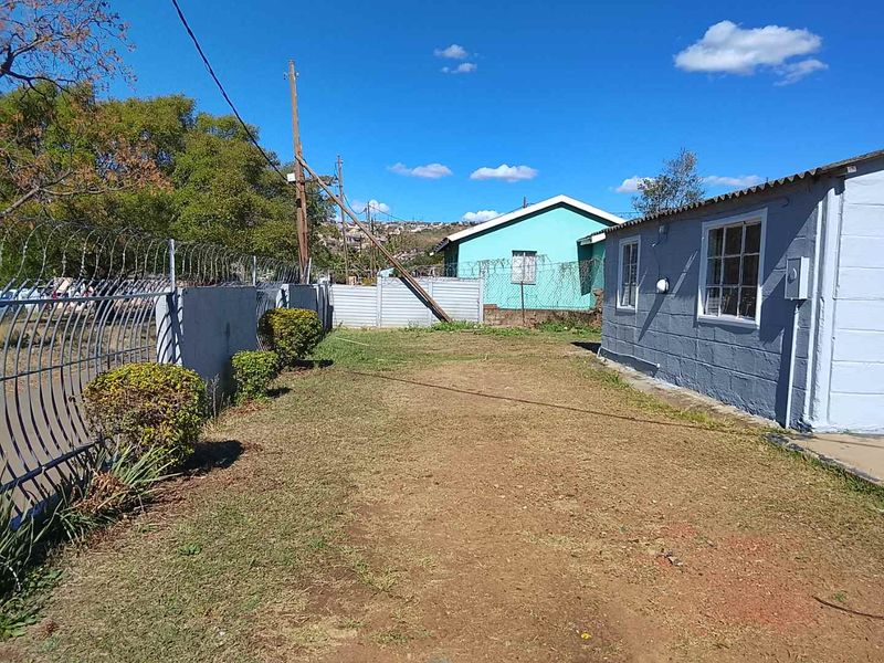 Rear exterior view of the property featuring a fenced yard area with concrete block walls and basic landscaping.