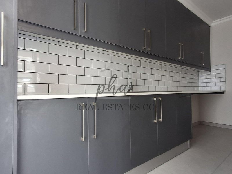 A modern kitchen featuring dark grey cabinetry, white subway tile backsplash, and a clean countertop finish.