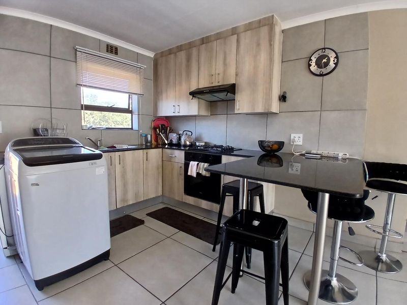 Modern kitchen featuring light wood-finish cabinetry, granite countertops, gas hob, electric oven, and tiled finishes throughout.