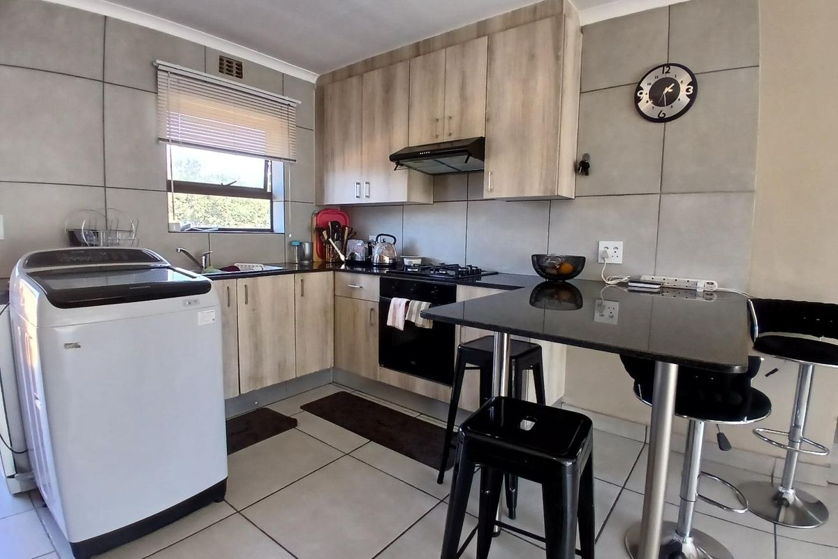 Modern kitchen featuring light wood-finish cabinetry, granite countertops, gas hob, electric oven, and tiled finishes throughout.