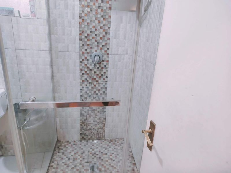 A modern bathroom shower area featuring a glass enclosure and decorative mosaic tile accents on the wall and floor.